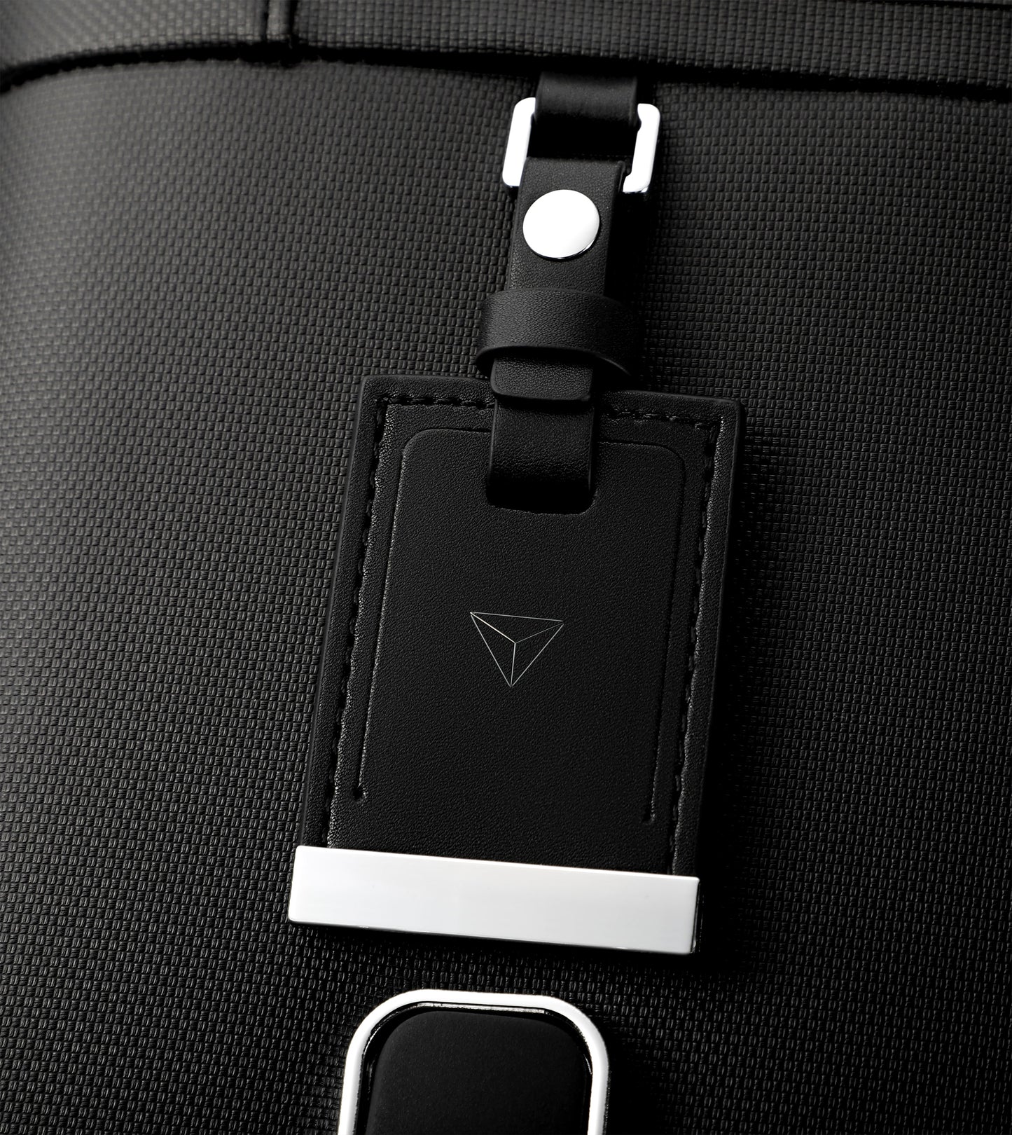 Black luggage tag attached to a black bag with a brand logo.