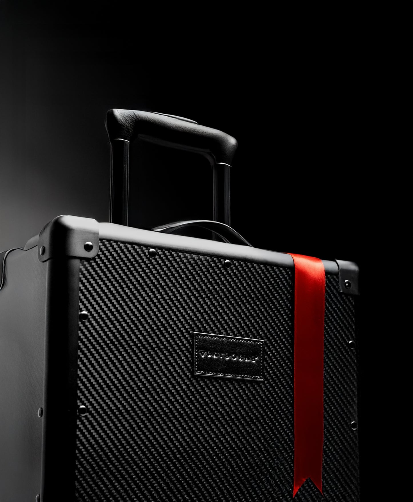Black suitcase with a red strap on a black background